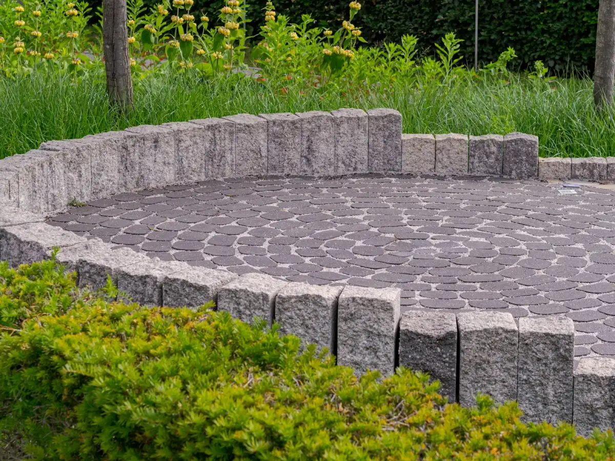 Circular paver patio with a block seat wall and planting around it